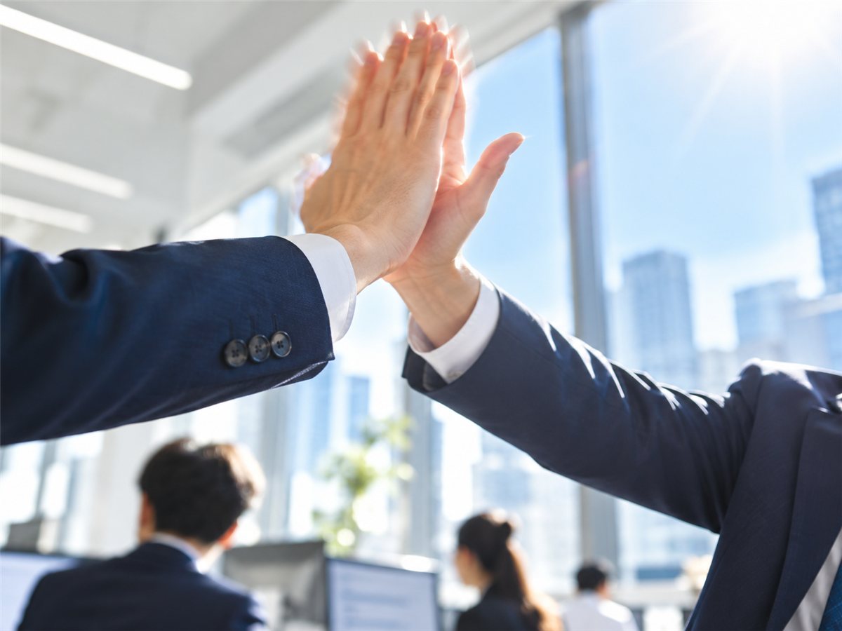 先輩とハイタッチする新人営業の手元